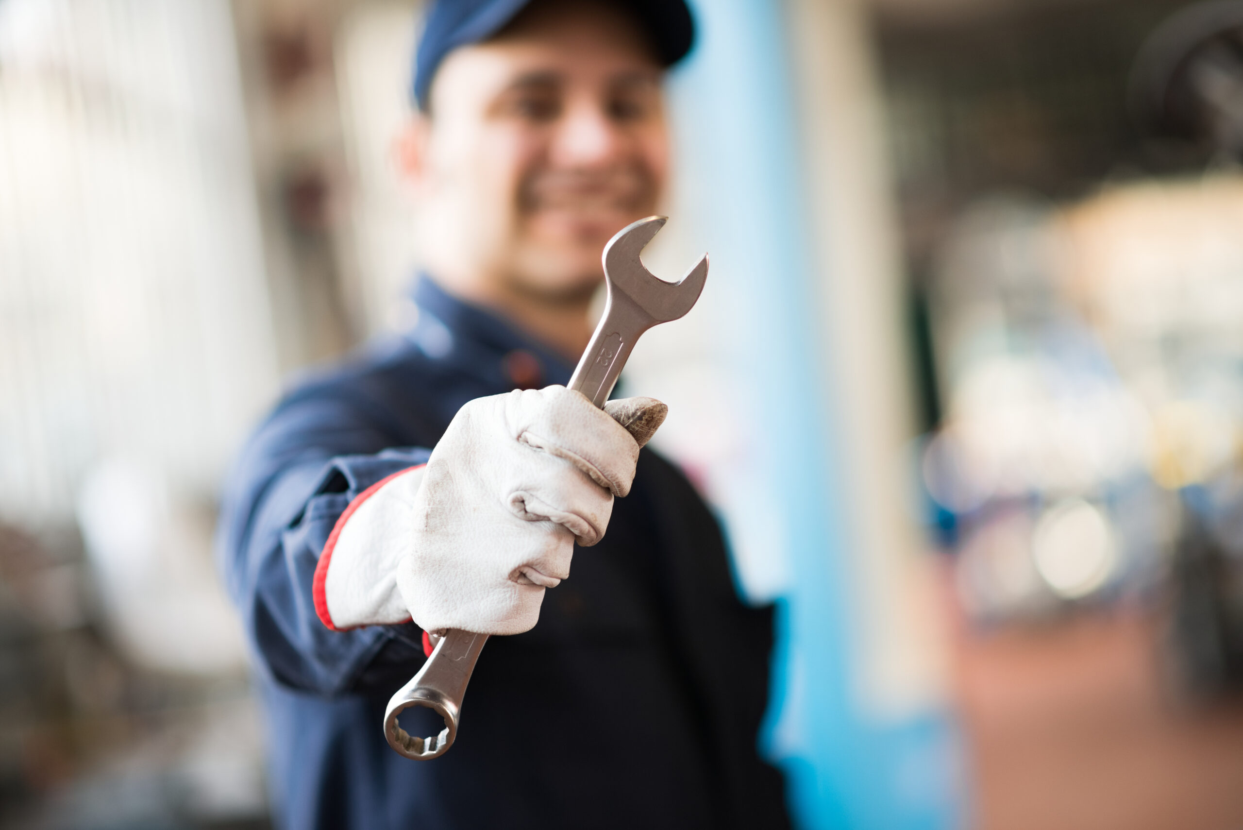 Smiling,mechanic,holding,a,wrench,in,his,shop